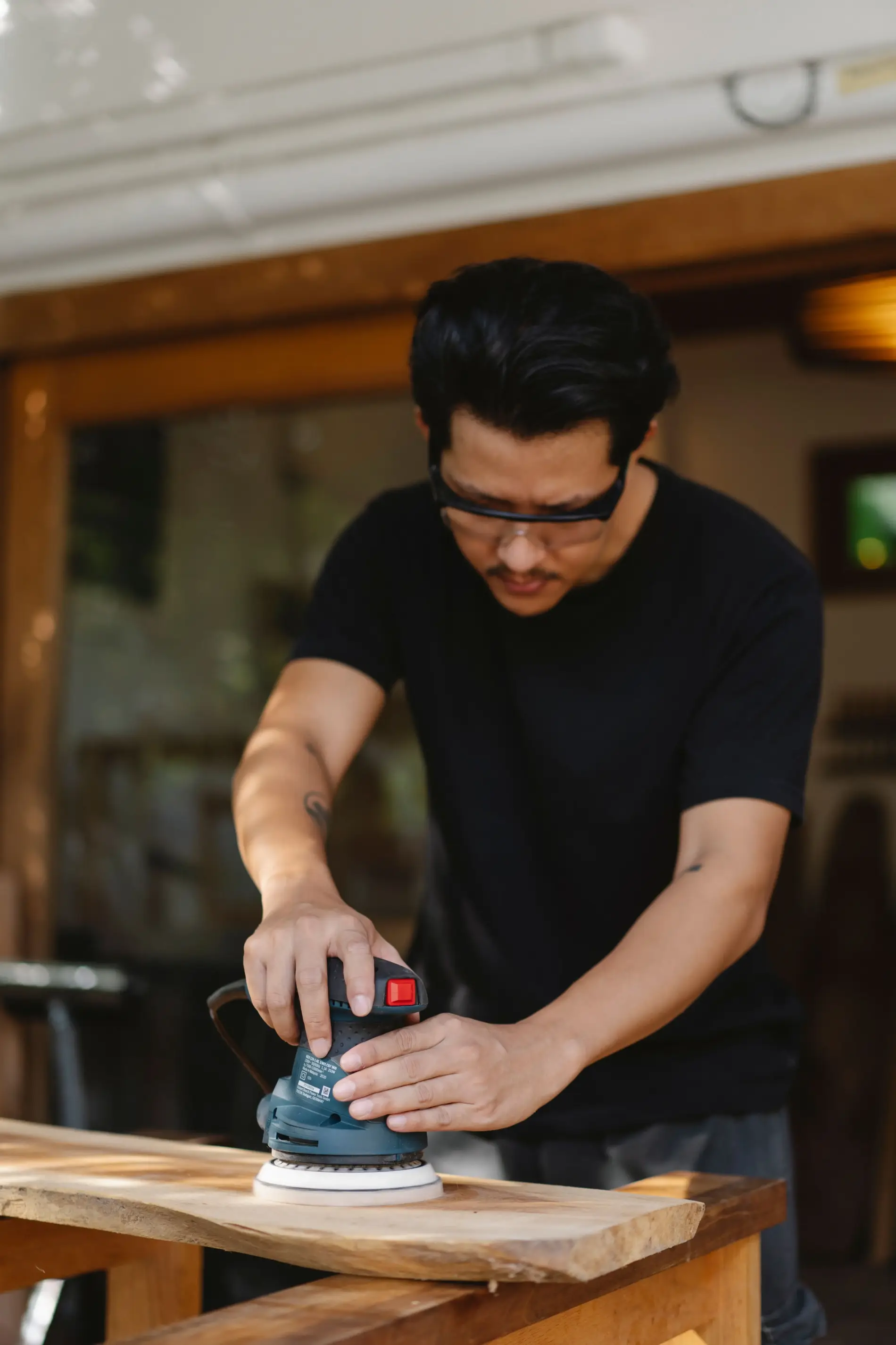 Craftsman sanding a timber tabletop in his workshop