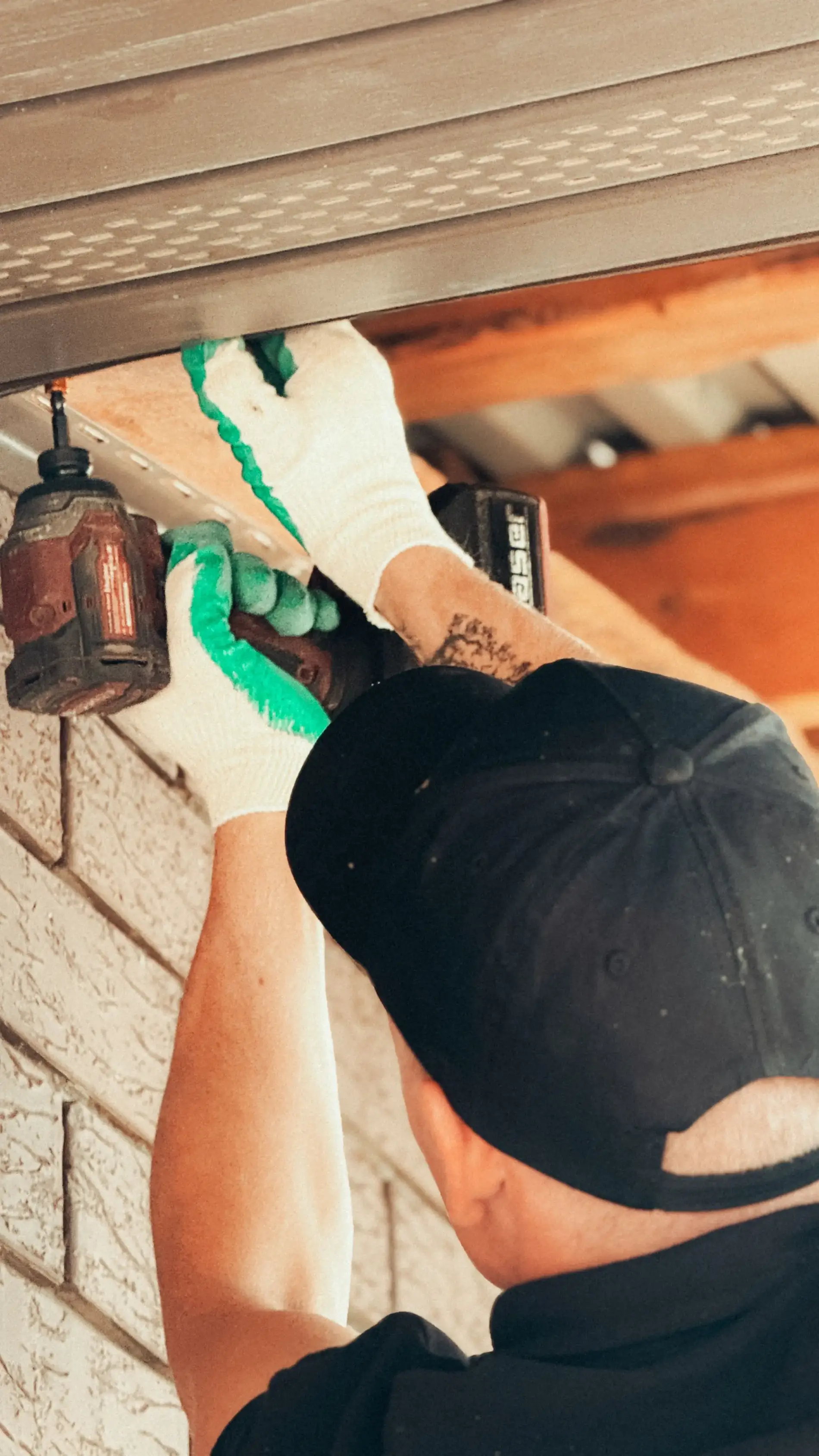 Handyman fastening an exterior fitting with a drill